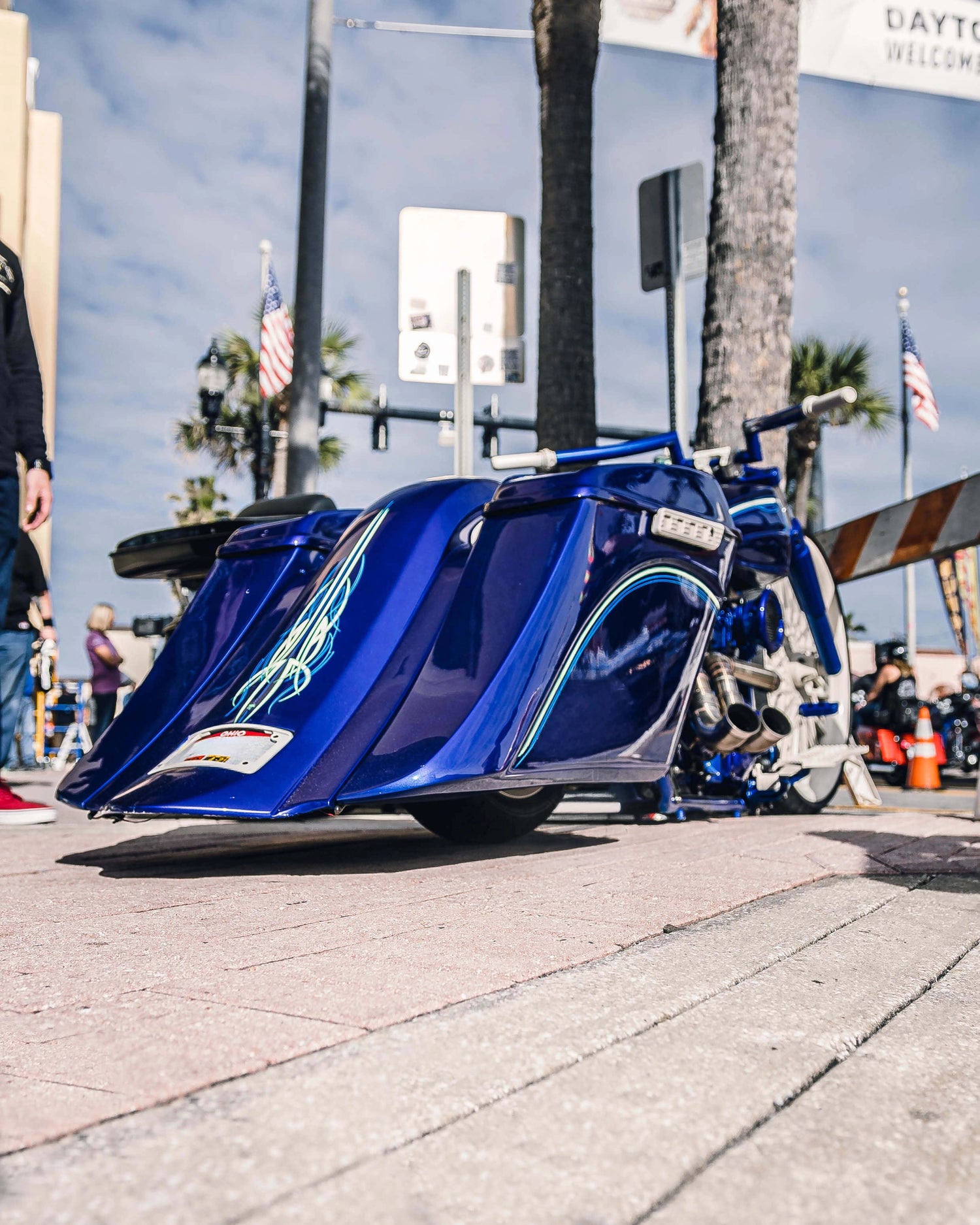 Blue motorcycle on a city street with palm trees and buildings in the background