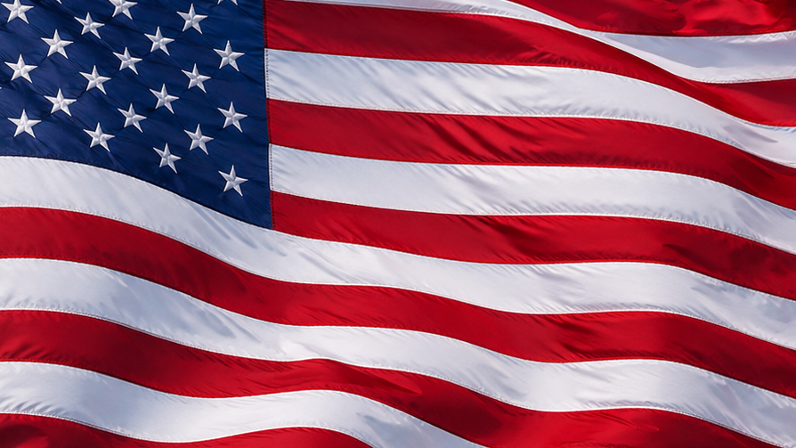 American flag waving against a blue sky with some clouds